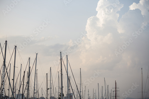 Yachts masts tops under Larnaca  s blue sky with fluffy clouds. Sky and town background.