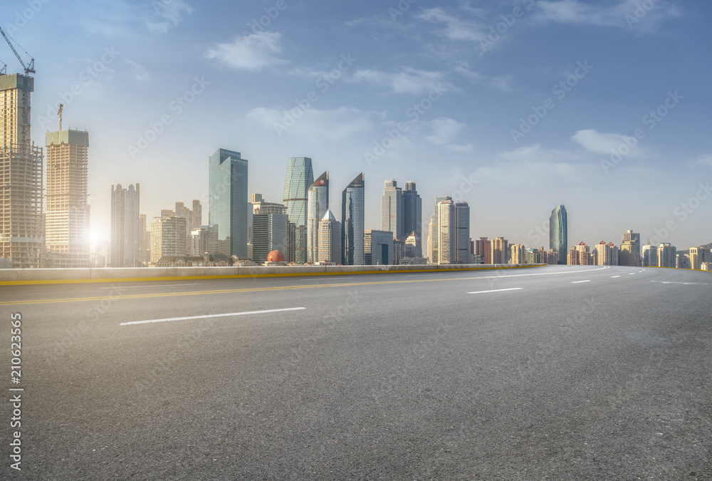 The empty asphalt road is built along modern commercial buildings in China's cities.