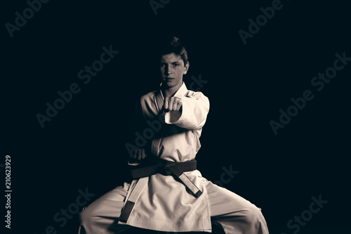 Young boy dressed in a white karate kimono with red belt.
