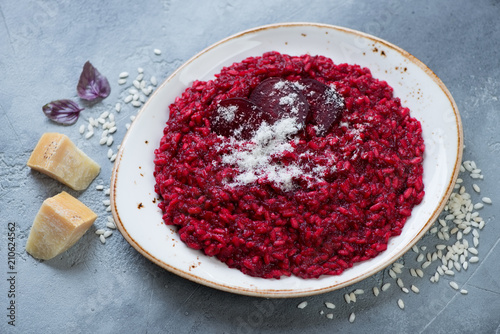 Plate of beetroot risotto with parmesan over grey concrete background, horizontal shot