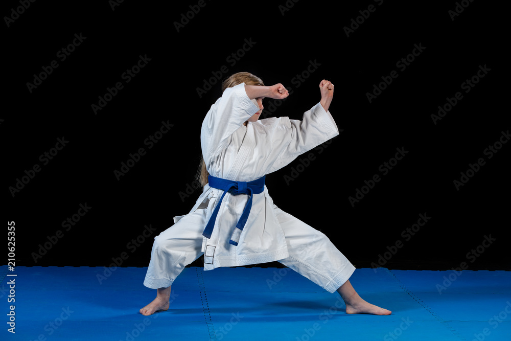 sweet little girl in martial arts practice like karate kid alone isolated on black background