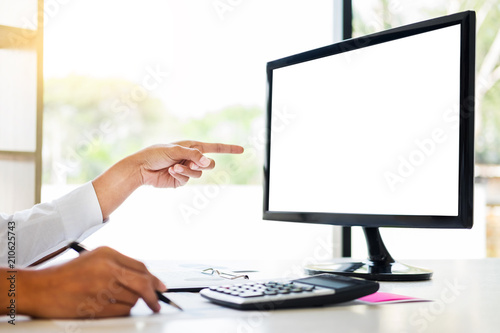 businessman working together pointing screen while discussing explaining a business analysis displayed on the monitor desktop PC with colleagues in the interior of a modern office.