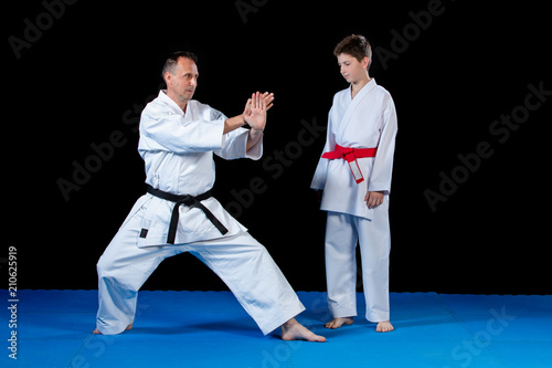 Male karate instructor training little children in dojo