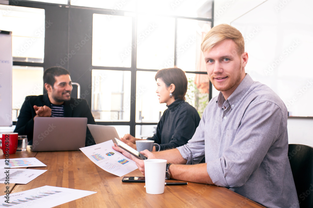Fototapeta premium Businessman looking to camera with attractive smile. People working at office place together.