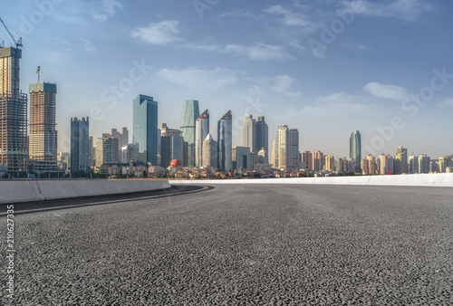 The empty asphalt road is built along modern commercial buildings in China s cities.