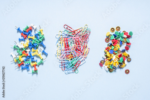 A set of stationery made of multi-colored buttons and paper clips in different piles