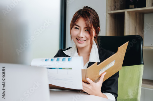 Asia business accounting concept, woman using smart phone and laptop computer to working finance and budget in office.