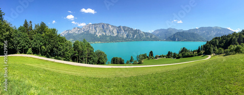 View to lake Attersee with green pasture meadows and Alps mountain range near Nussdorf Salzburg, Austria photo