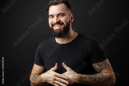 Happy young man. Portrait of handsome young man in casual shirt keeping arms crossed and smiling while standing against black background. photo