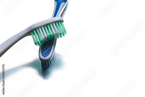 Blue and green toothbrush on a shiny gray background