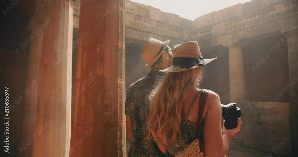 Young tourists couple in Greece taking photos of ancient columns