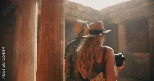 Young tourists couple in Greece taking photos of ancient columns