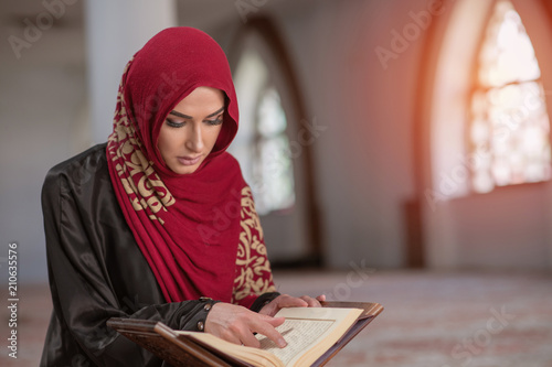 Muslim Woman Reading Koran Or Quran Wearing Traditional Dress At The Mosque