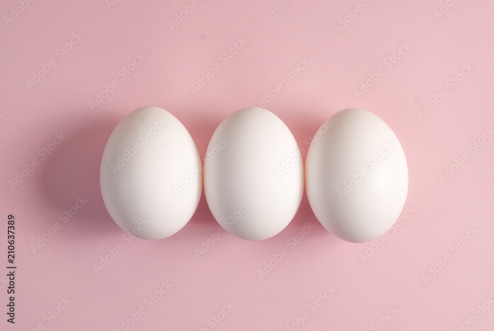 Group of three white eggs on a pink background