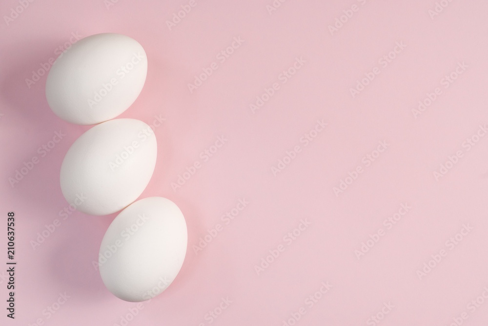 Group of three white eggs on a pink background