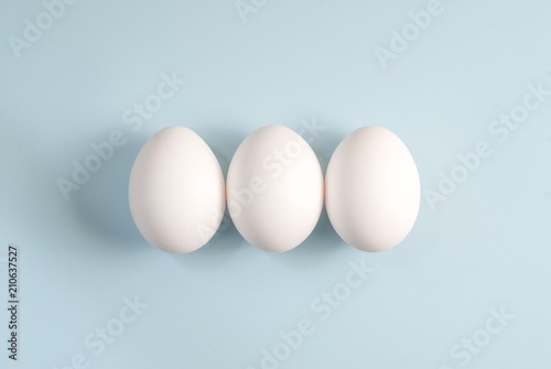 Three white eggs on a blue background