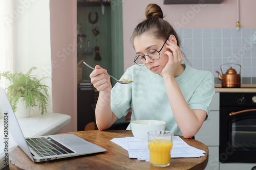 No appetite. Frustrated bored young woman looking at bowl with some tasteless cereal. Heathy but flavorless food, dislike concept. photo