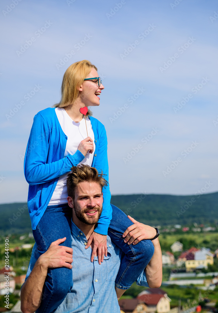 Idyllic date concept. Man carries girlfriend on shoulders, sky background. Couple in love enjoy perfect date sunny day. Couple happy date having fun together. Woman enjoy perfect romantic date