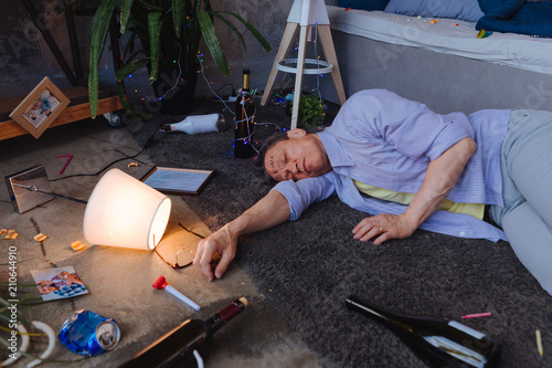 Φωτογραφία Alcohol effect. Drunken mature man lying on floor and dreaming