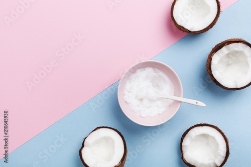 Coconut oil with fresh coconuts fruit on minimal pastel background top view. Natural and organic beauty cosmetic. Flat lay.