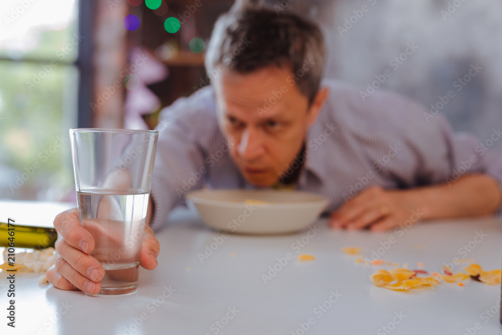 Casual drinking. Selective focus of cold clear water pouring in glass which standing on table Casual drinking. Selective focus of cold clear water pouring in glass which standing on table