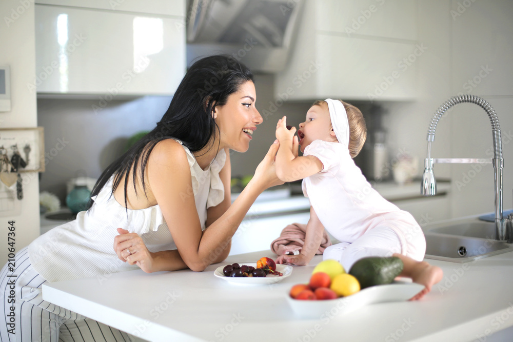 Mother giving food to her baby in the kitchen