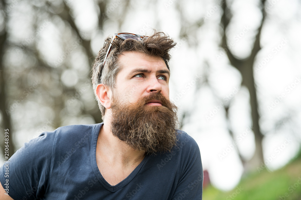 Man with long beard and mustache wears sunglasses on head, defocused background. Guy looks cool with stylish beard and haircut. Barbershop concept. Hipster with beard with gray on thoughtful face Man with long beard and mustache wears sunglasses on head, defocused background. Guy looks cool with stylish beard and haircut. Barbershop concept. Hipster with beard with gray on thoughtful face