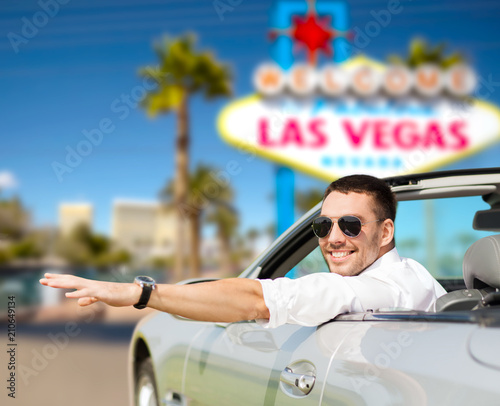 road trip, travel and people concept - happy man driving convertible car over welcome to fabulous las vegas sign background