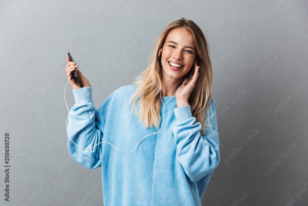 Portrait of a smiling young blonde girl listening to music Stock Photo ...