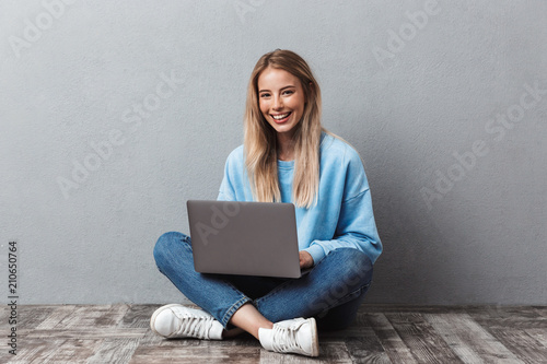 Smiling young blonde girl using laptop computer