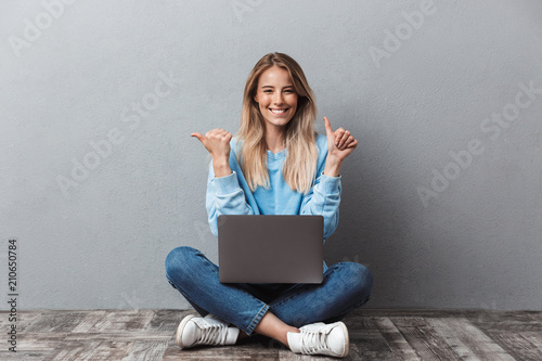 Happy young blonde girl using laptop computer photo