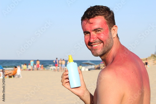 Man showing tanning lotion while getting sunburned
