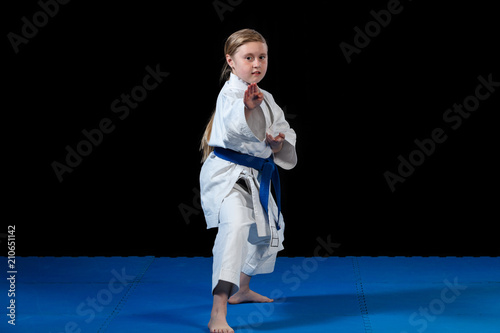 sweet little girl in martial arts practice like karate kid alone isolated on black background