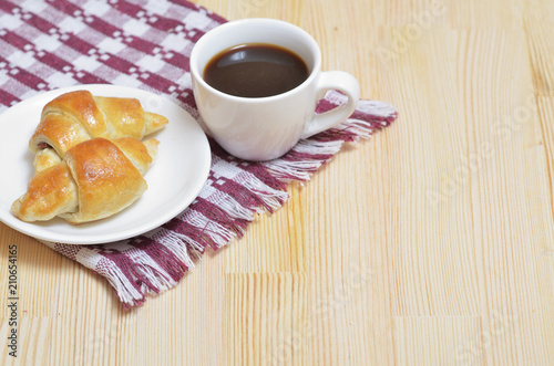 Croissants on a white plate, a cup of coffee