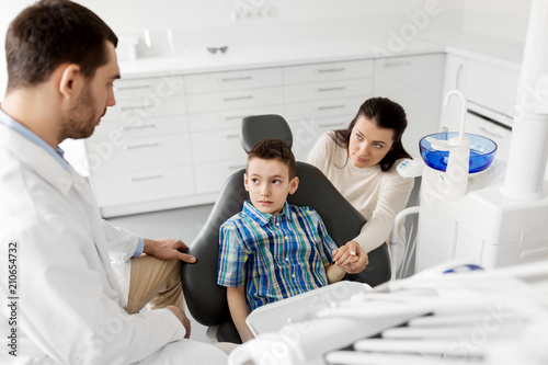 medicine  dentistry and healthcare concept - mother and son visiting dentist at dental clinic