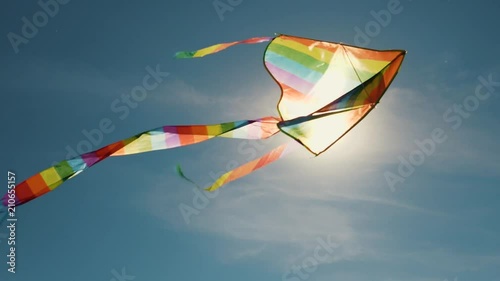 A colored kite in the blue sky. Slowed-down shooting of a kite developing against a blue sky and white clouds