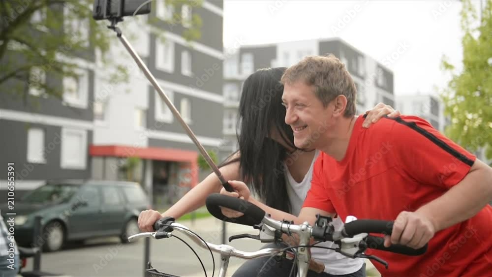 Couple In Love Taking Selfie. They Sit On Bicycle. They Hug and Flirt with Each Other. Couple In Love Taking Selfie. They Sit On Bicycle. They Hug and Flirt with Each Other.