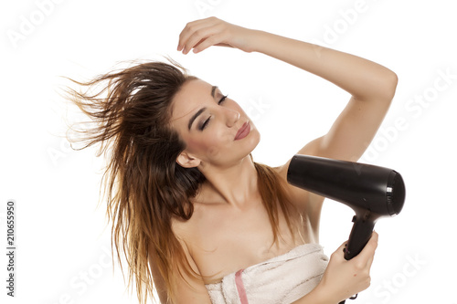 young beautiful woman drying her hair with a blow dryer on a white background