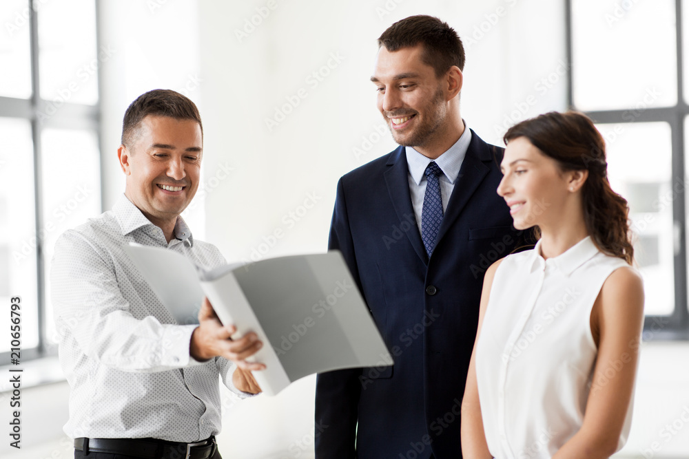real estate business, sale and people concept - happy smiling realtor with folder showing documents to customers at new office room real estate business, sale and people concept - happy smiling realtor with folder showing documents to customers at new office room