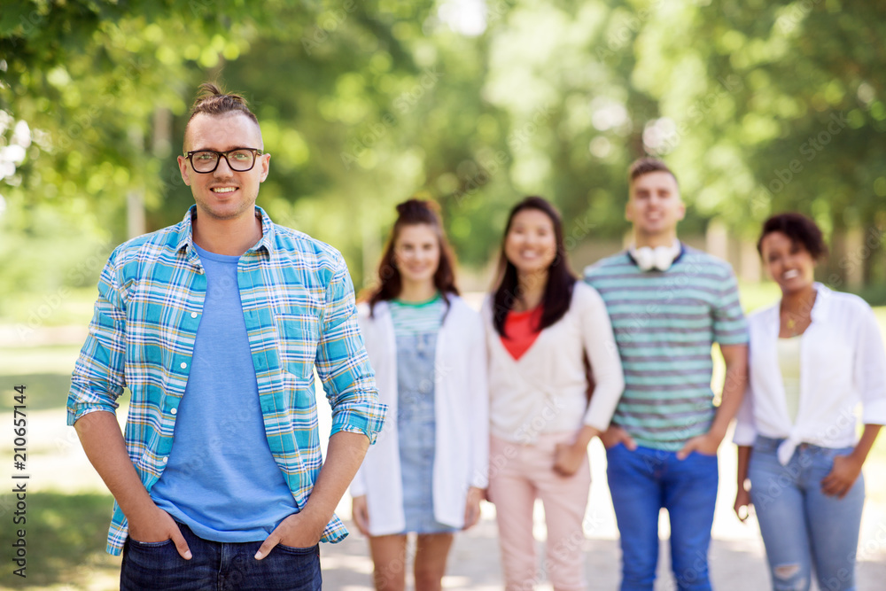 people, friendship and international concept - happy smiling young man and group of happy friends outdoors