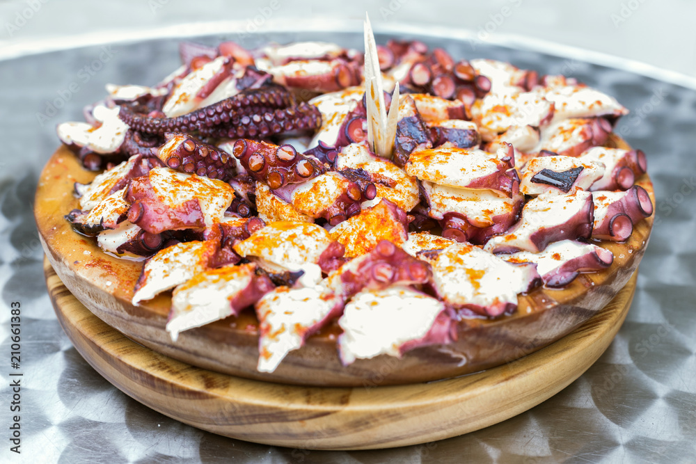Wooden plate of galician style cooked octopus with paprika and olive oil. Pulpo a la gallega Wooden plate of galician style cooked octopus with paprika and olive oil. Pulpo a la gallega
