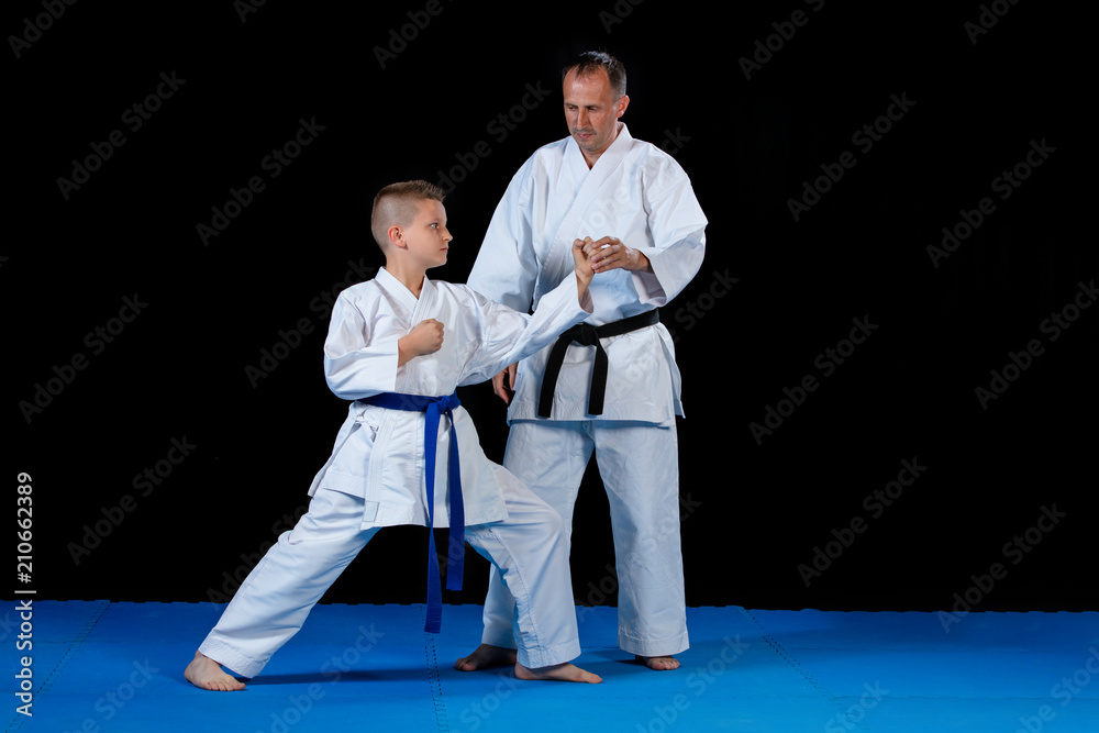 Male karate instructor training little children in dojo