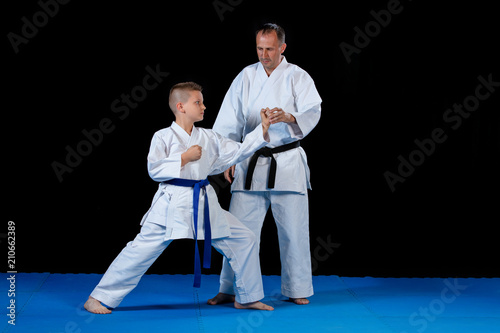 Male karate instructor training little children in dojo