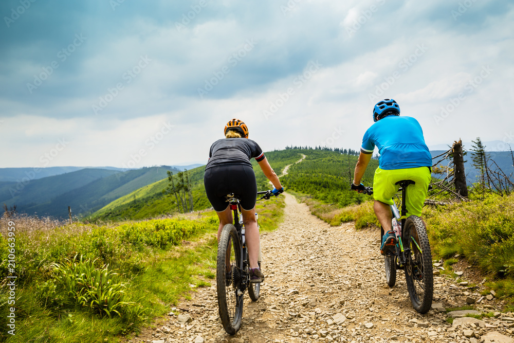 Fototapeta premium Cycling woman and man at Beskidy mountains forest landscape. Couple riding MTB enduro track. Outdoor sport activity.