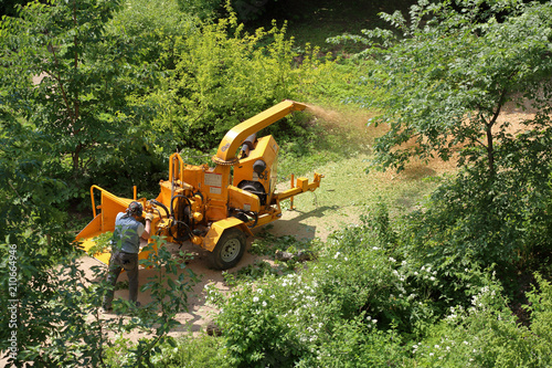Mobile yellow wood and branches shredder in the city park
