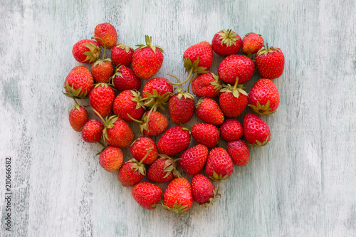 Fresh heart-shaped strawberries on wooden background.