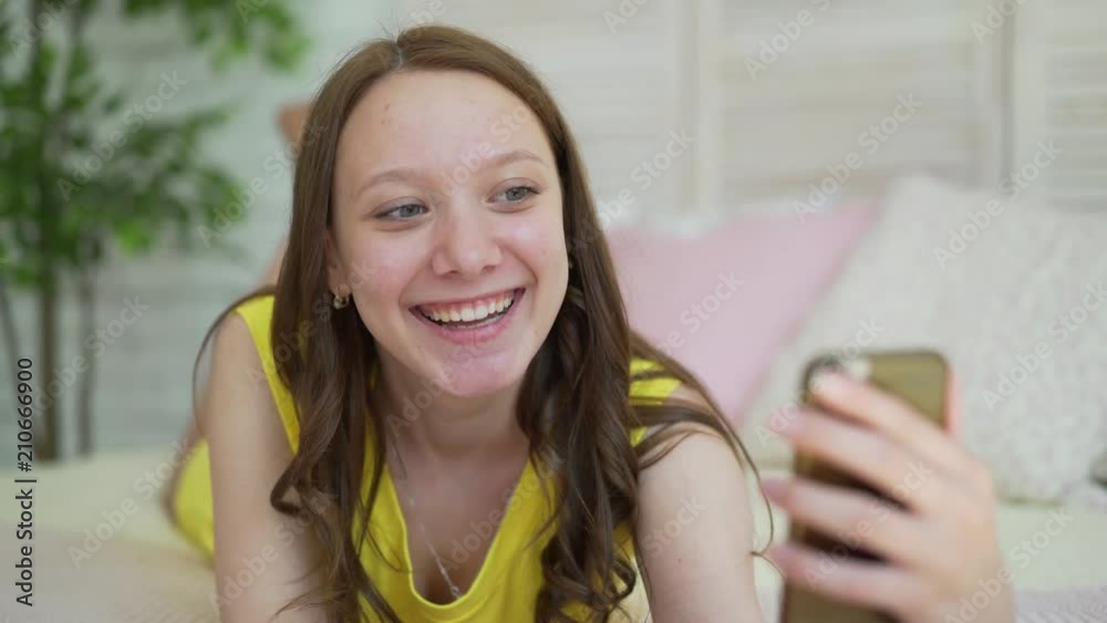 Young Woman Using Cell Smart Phone Happy Smiling Beautiful Girl Lying On Bed In Bedroom Morning Young Woman Using Cell Smart Phone Happy Smiling Beautiful Girl Lying On Bed In Bedroom Morning