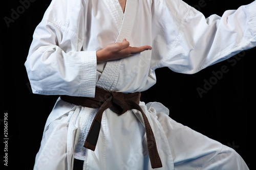 Young boy training karate on black background