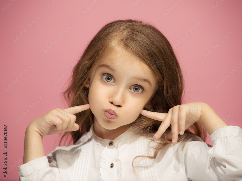 The happy teen girl standing and smiling against pink background. The happy teen girl standing and smiling against pink background.