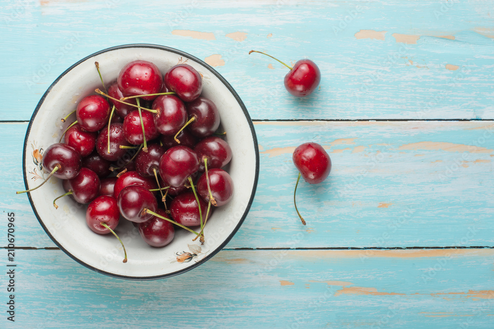 Sweet cherries in a bowl, on a blue wooden background